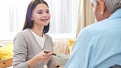 Betreuungswelt-Friesch Senior wird von einer Betreuungskraft beim Essen unterstützt
