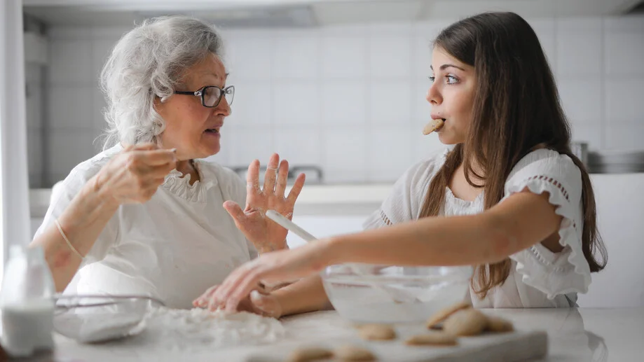 Betreuungswelt-Friesch Seniorin und Betreuungskraft sitzen am Tisch und unterhalten sich bzw. backen