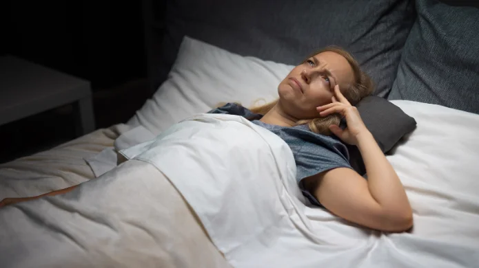 Schlafstörungen ab 50 Eine reifere Frau liegt nachts wach im Bett, blickt nachdenklich an die Decke und stützt den Kopf auf die Hand – Illustration zu Schlafstörungen ab 50.