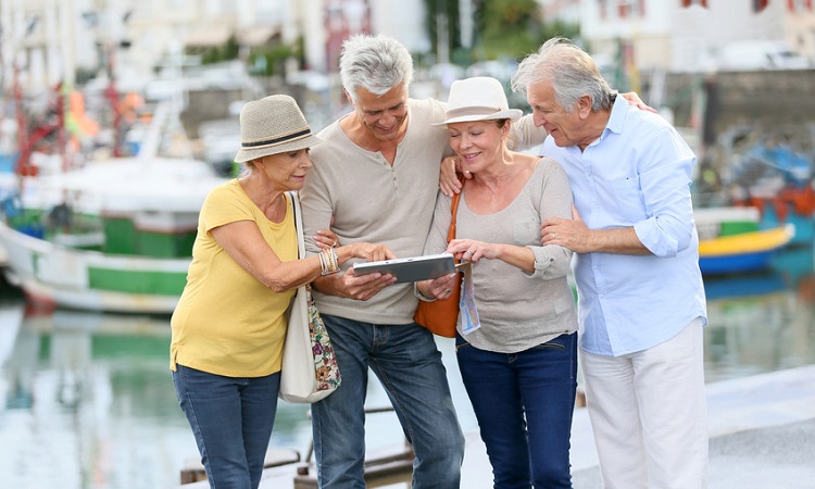 Eine kleine Gruppe von zwei Frauen und zwei Männern sehen gebannt auf eine Stadtkarte und ein Tablet mit welchem Sie sich in der Stadt zurecht finden wollen. 