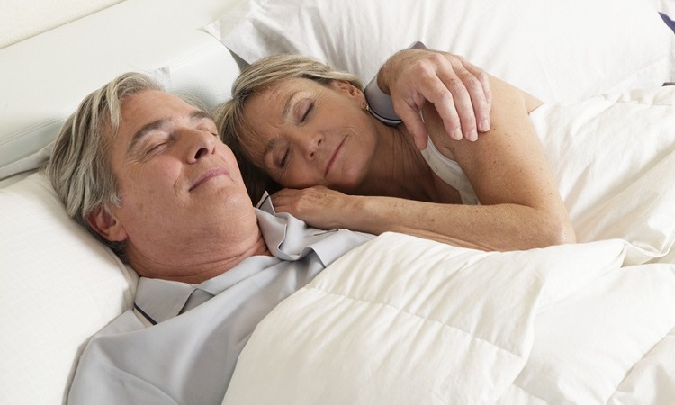 Älteres Paar liegt schlafend im Bett. 