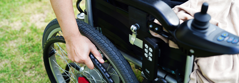 Eine mittelalte Person bedient einen Elektro-Rollstuhl 