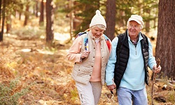 Älteres Paar geht im Wald mit Rucksäcken wandern.
