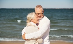 Älteres Paar umarmt sich am Strand – Blasenschwäche.