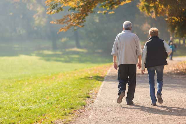 Senioren gehen nebeneinander, augenscheinlich als Paar, spazieren.