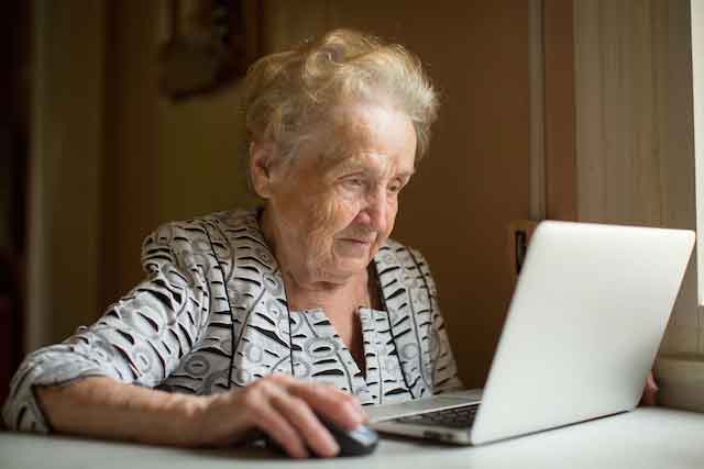 Seniorin surft am Laptop im Internet.