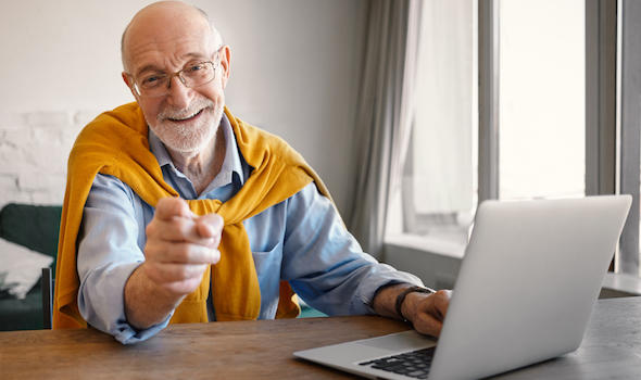 fashionable-friendly-elderly-male-recruiter-wearing-rectangular-glasses-and-elegant-clothes-working-on-portable-computer-smiling-broadly-and-pointing-finger-choosing-you-for-job-position.jpeg
