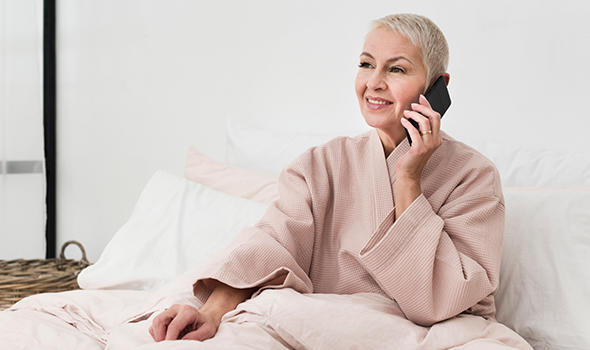 Freepik_happy-elderly-woman-in-bathrobe-talking-on-smartphone-in-bed_freepik.jpg