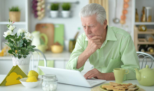 senior-man-sitting-at-table-in-kitchen-and-using-modern-laptop.jpeg
